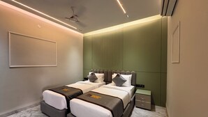 A modern bedroom with a bed, bedside tables, and a ceiling fan. - Hotel Mumbai House - Pithampur (Pithampur)