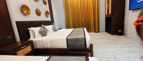 A hotel room with a bed, a TV, and a large window with curtains.