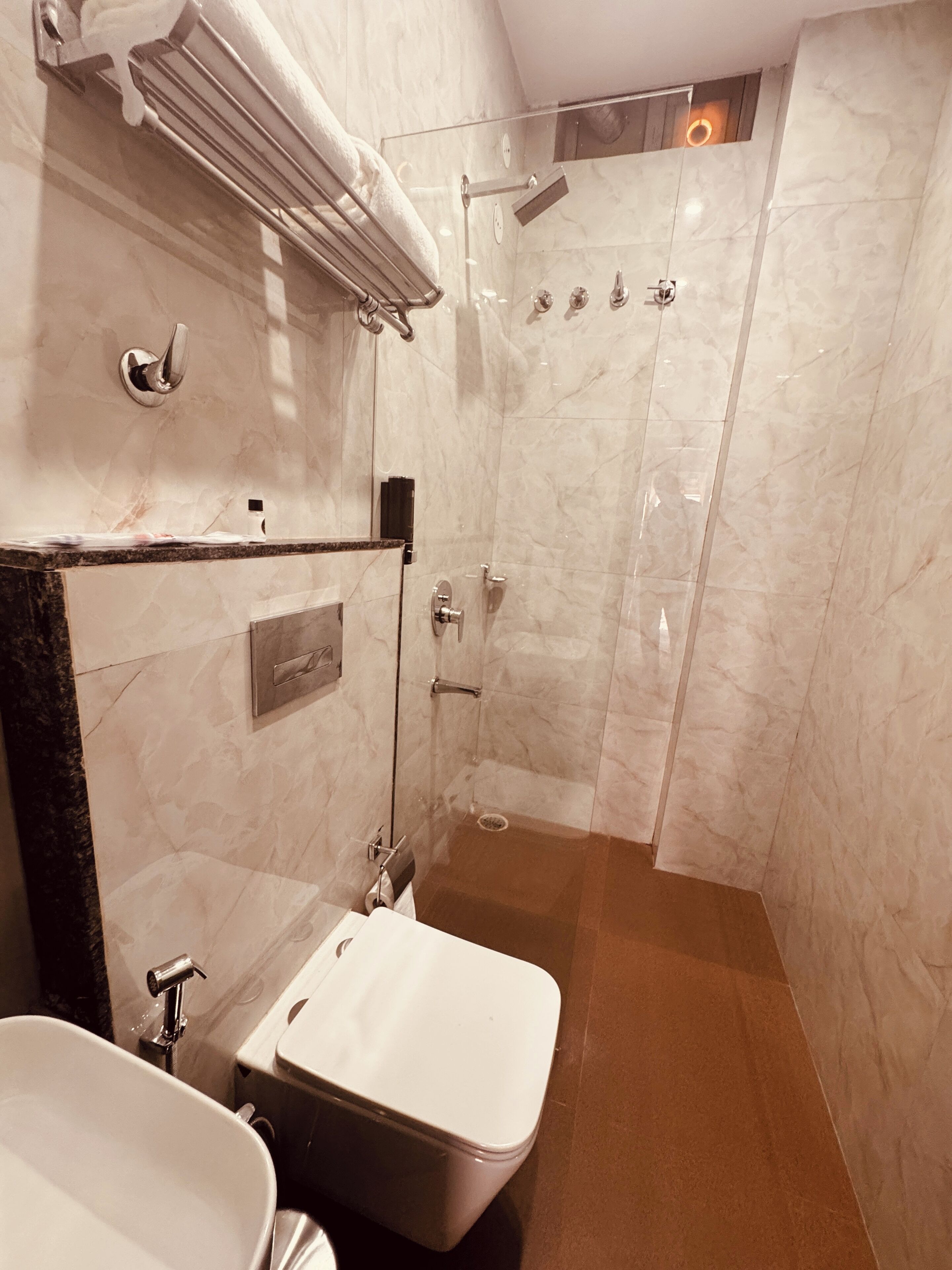Un baño moderno con ducha de vidrio, lavamanos con encimera de mármol y retrete.