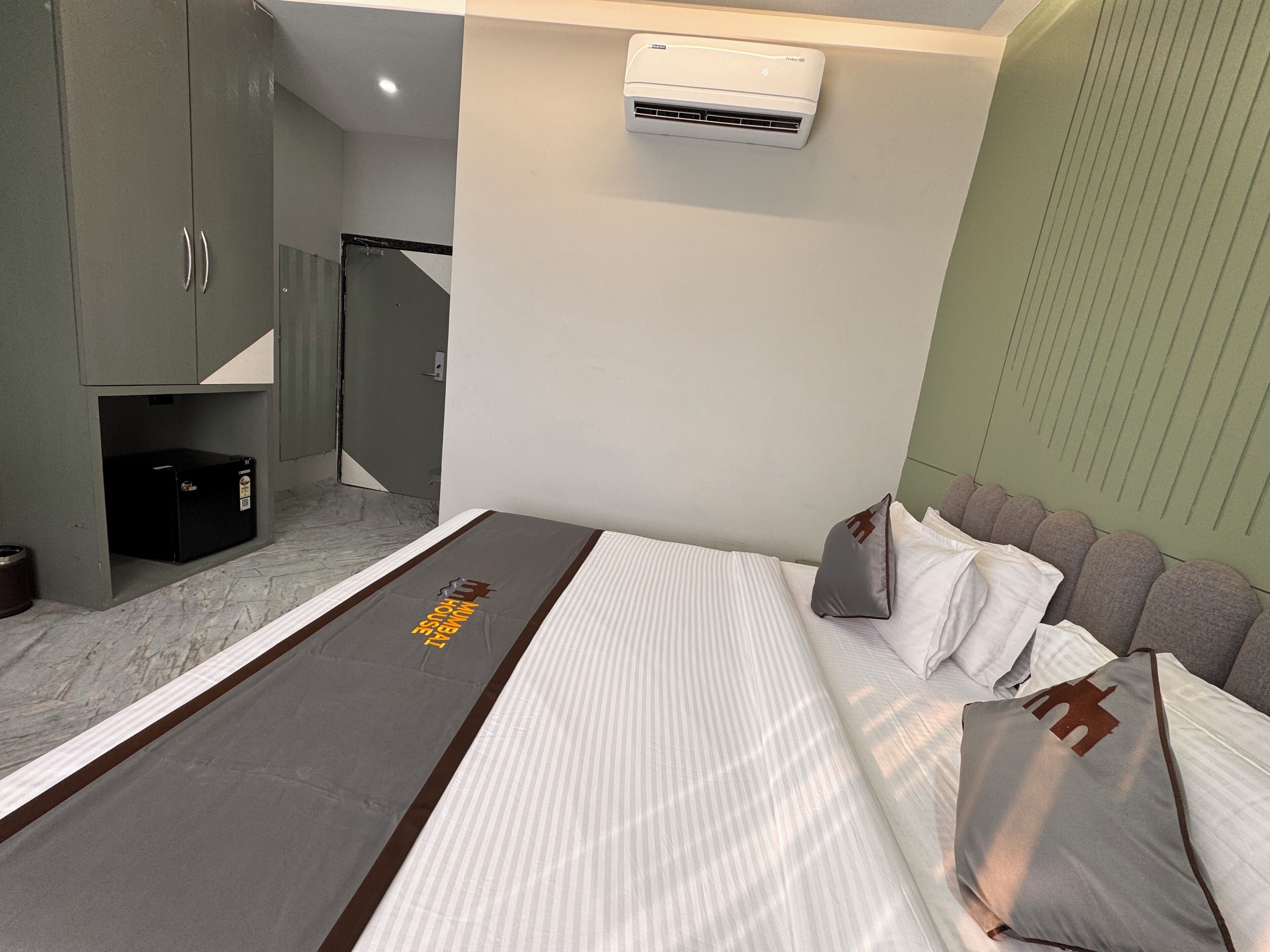 Une chambre d’hôtel équipée d’un lit, d’un petit bureau, d’une armoire et d’un appareil de climatisation.