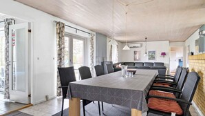Ein moderner Essbereich mit einem rechteckigen Tisch, schwarzen Stühlen und einer grauen Tischdecke mit Muster.