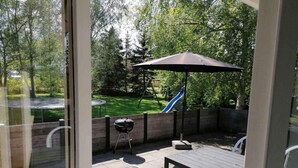 Eine Terrasse im Freien mit Tisch und Stühlen, einem Grill und einer Schaukel.