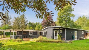 A modern cabin with a covered porch, a small deck, and a well-maintained lawn. - 4 Star Holiday Home in Hojslev (Hojslev)