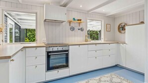 A modern kitchen with white cabinetry, a built-in oven, and a large window. - 4 Star Holiday Home in Hojslev (Hojslev)