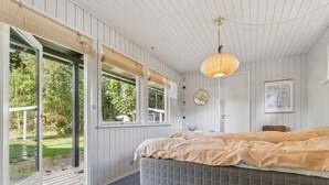 A bedroom with a large bed, a window with a view of the outdoors, and a hanging light fixture. - 4 Star Holiday Home in Hojslev (Hojslev)