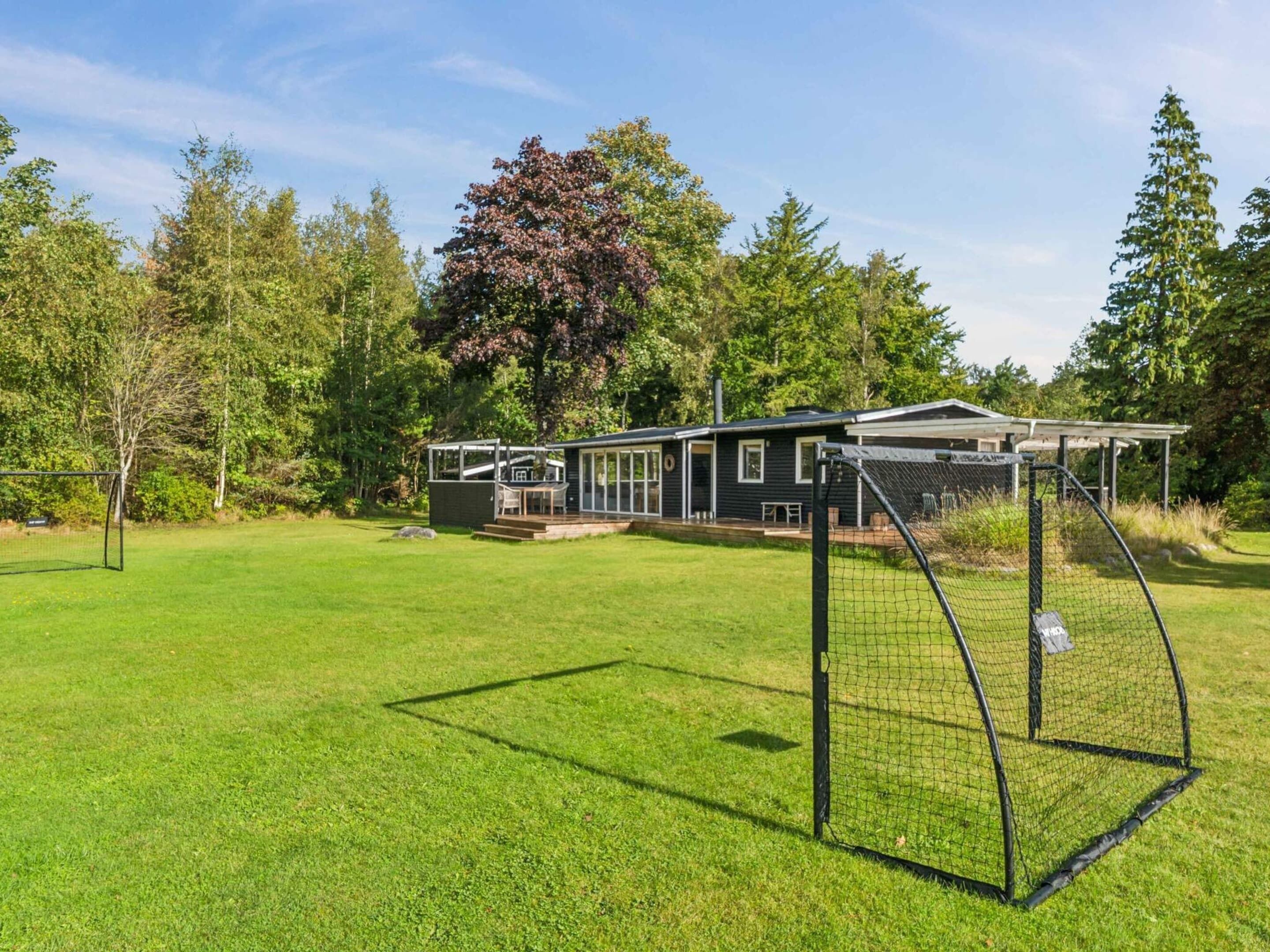 A modern house with a large fenced yard, a patio, and a well-maintained lawn.
