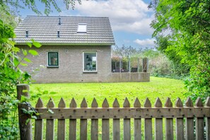 A two-story house with a tiled roof, a visible chimney, and a fenced backyard. - Tastefully and Modernly Furnished 5-person Bungalow (De Waal)
