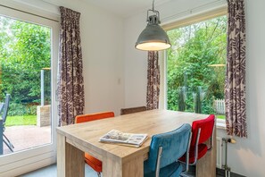 A dining area with a wooden table, four chairs, and a hanging light fixture. - Tastefully and Modernly Furnished 5-person Bungalow (De Waal)
