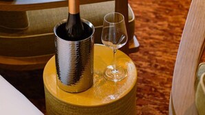 A room with a wooden chair, a small round table with a bottle of champagne and a glass on it. - Confidential Room 3, a Stone's Throw From the Louvre (Paris)
