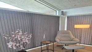 Une pièce moderne avec un mur gris, un canapé gris, une petite table ronde et un lampadaire.
