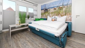 A modern bedroom with a bed, a bench, and a large beach mural on the wall. - Moderne Ferienwohnung in Ruhiger Lage, Bensersiel (Esens)