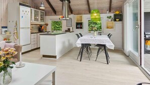 A modern kitchen with a central island, a dining area with a table and chairs, and a view of the outdoors through a skylight. - 4 Star Holiday Home in Hurup Thy (Hurup Thy)
