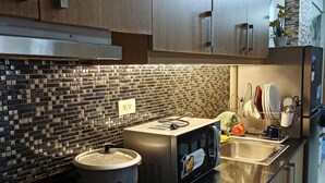 Une cuisine moderne avec des meubles en bois, un pare-feu en carreaux, une cuisinière, un four à micro-ondes et un évier.