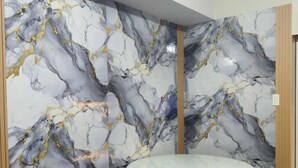 Une pièce avec un mur décoré d’un motif imitant le marbre, une table ronde et deux chaises noires.
