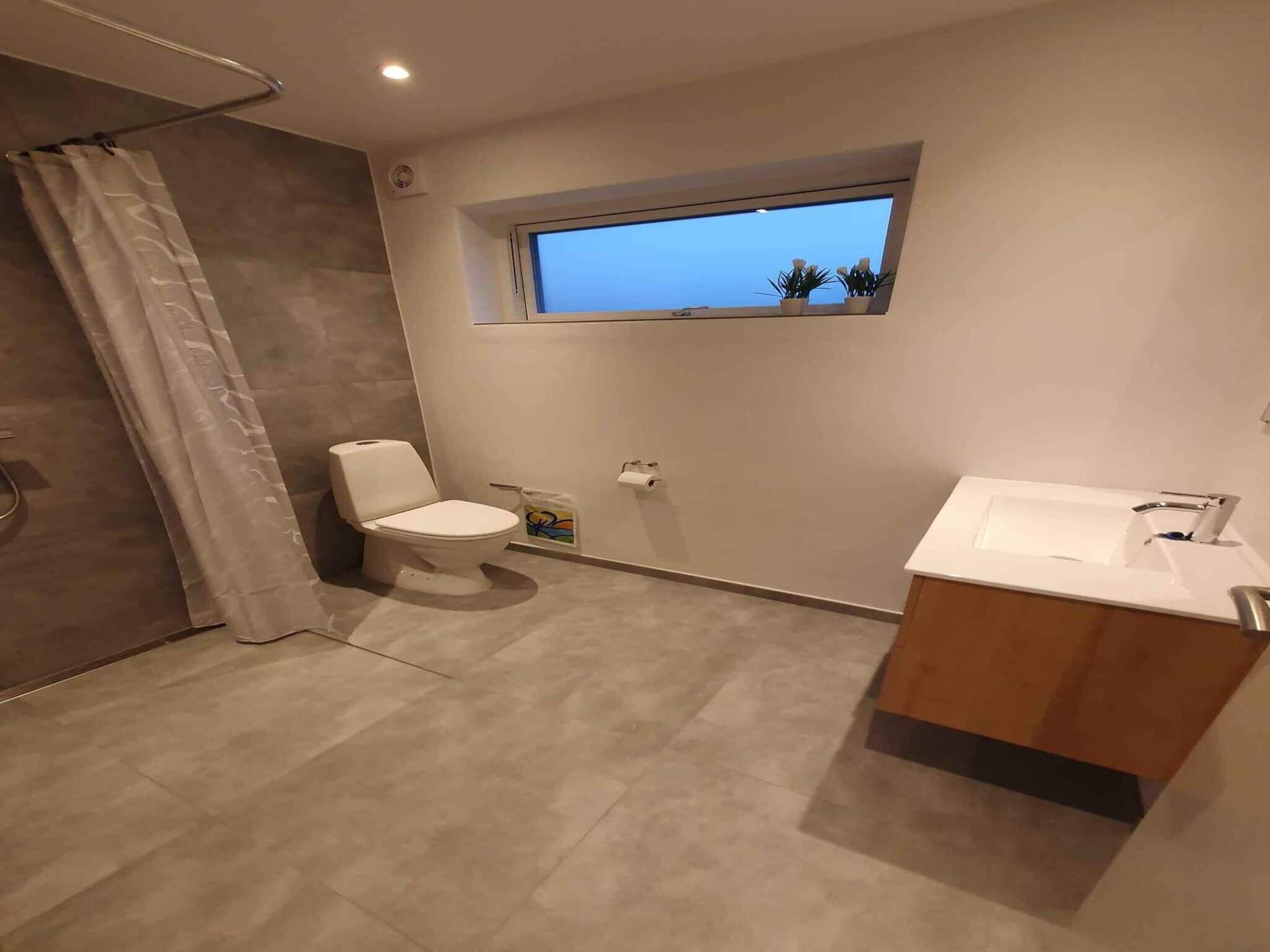 Une salle de bain moderne avec des toilettes, une fenêtre et un lavabo.