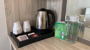 A coffee station with a kettle, mugs, and a sign promoting the use of water bottles. - The Baliem Hotel (Jimbaran)