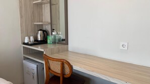 A compact kitchenette with a microwave, kettle, and coffee maker. There is a small refrigerator and a chair with a woven backrest. - The Baliem Hotel (Jimbaran)