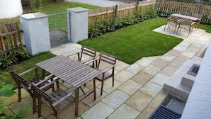 A patio with wooden tables and chairs, a small lawn, and a wooden fence. - Vacation apartment on Lake Starnberg In the town center, just a few minutes from the lake (Seeshaupt)