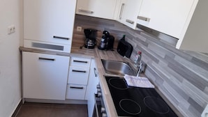 A compact kitchen with white cabinets, a built-in stove, and a sink. - Vacation apartment on Lake Starnberg In the town center, just a few minutes from the lake (Seeshaupt)