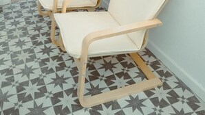 Una stanza con due poltrone beige davanti a un muro con mobili contenitori in legno.