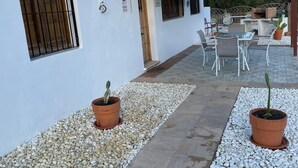 Un portico con posti a sedere all'aperto, piante in vaso e un vialetto che conduce all'ingresso di un edificio.