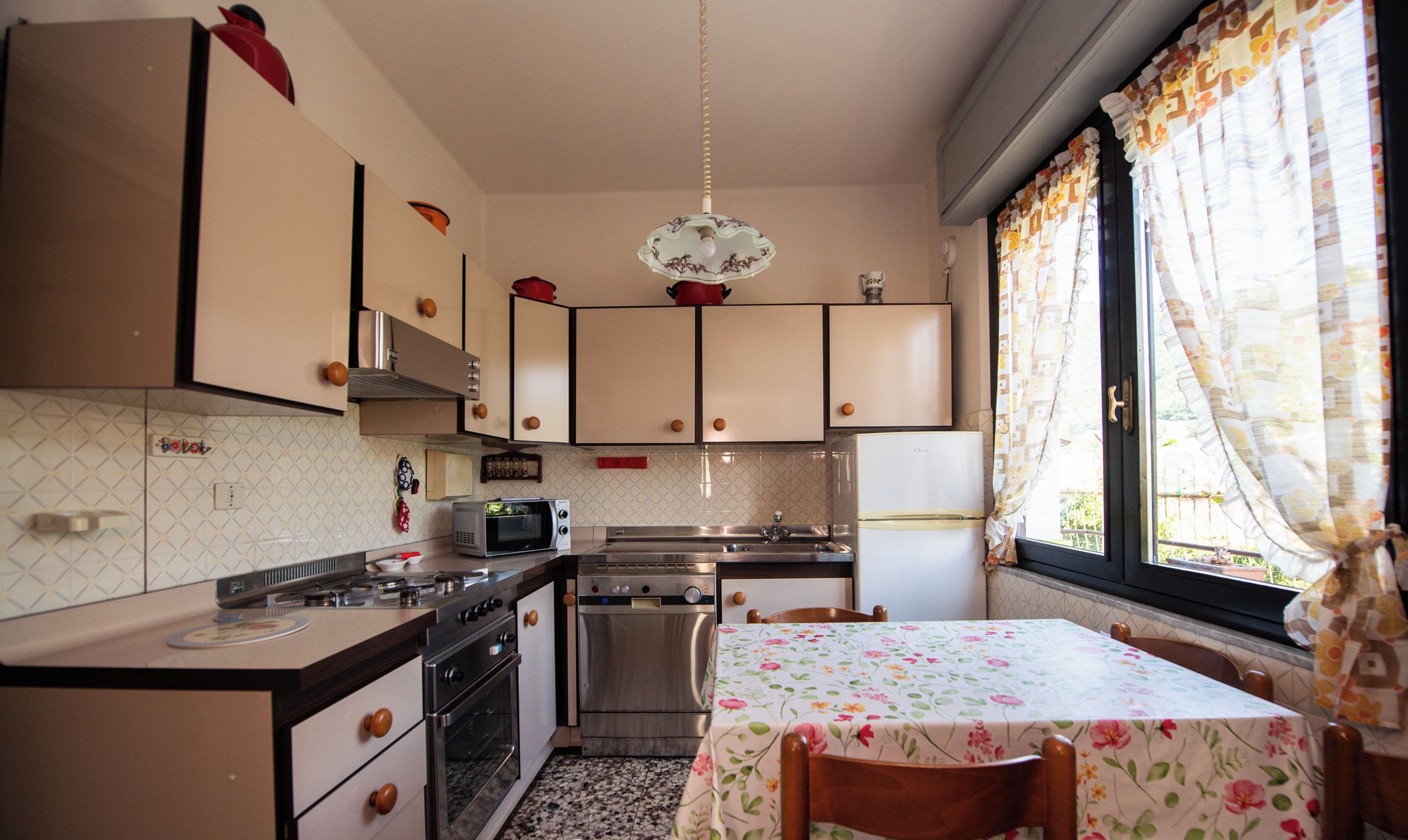 Una cocina con una mesa de comedor, armarios, microondas y un lavabo.