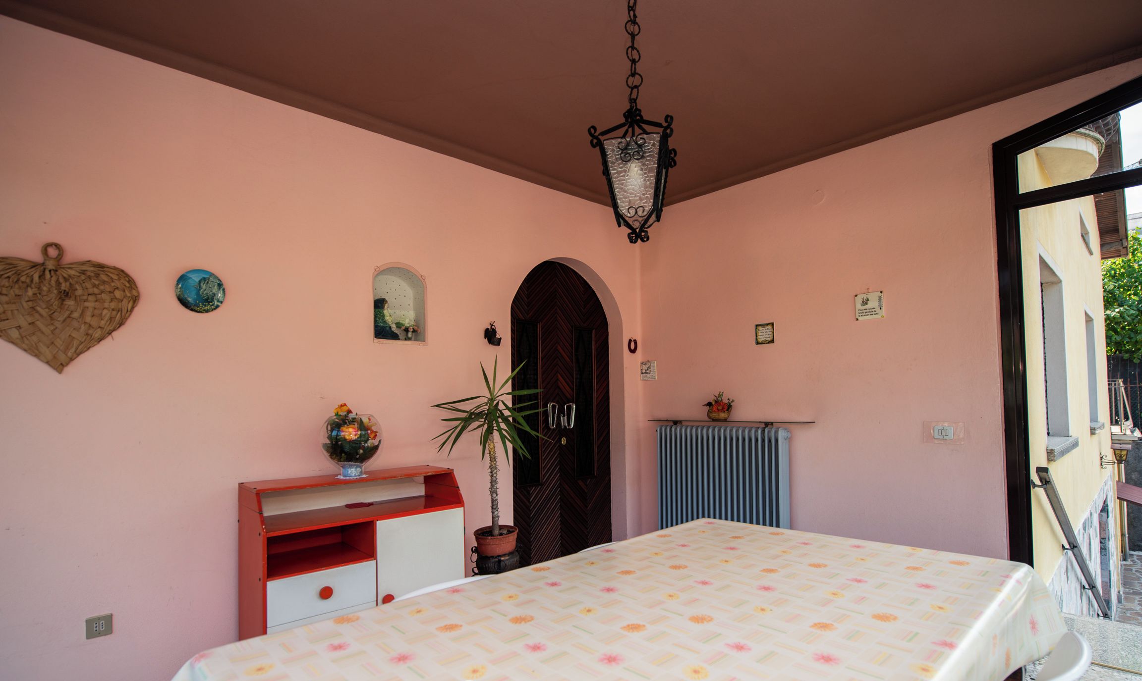 A bedroom with a bed, a dresser, a potted plant, and a door.