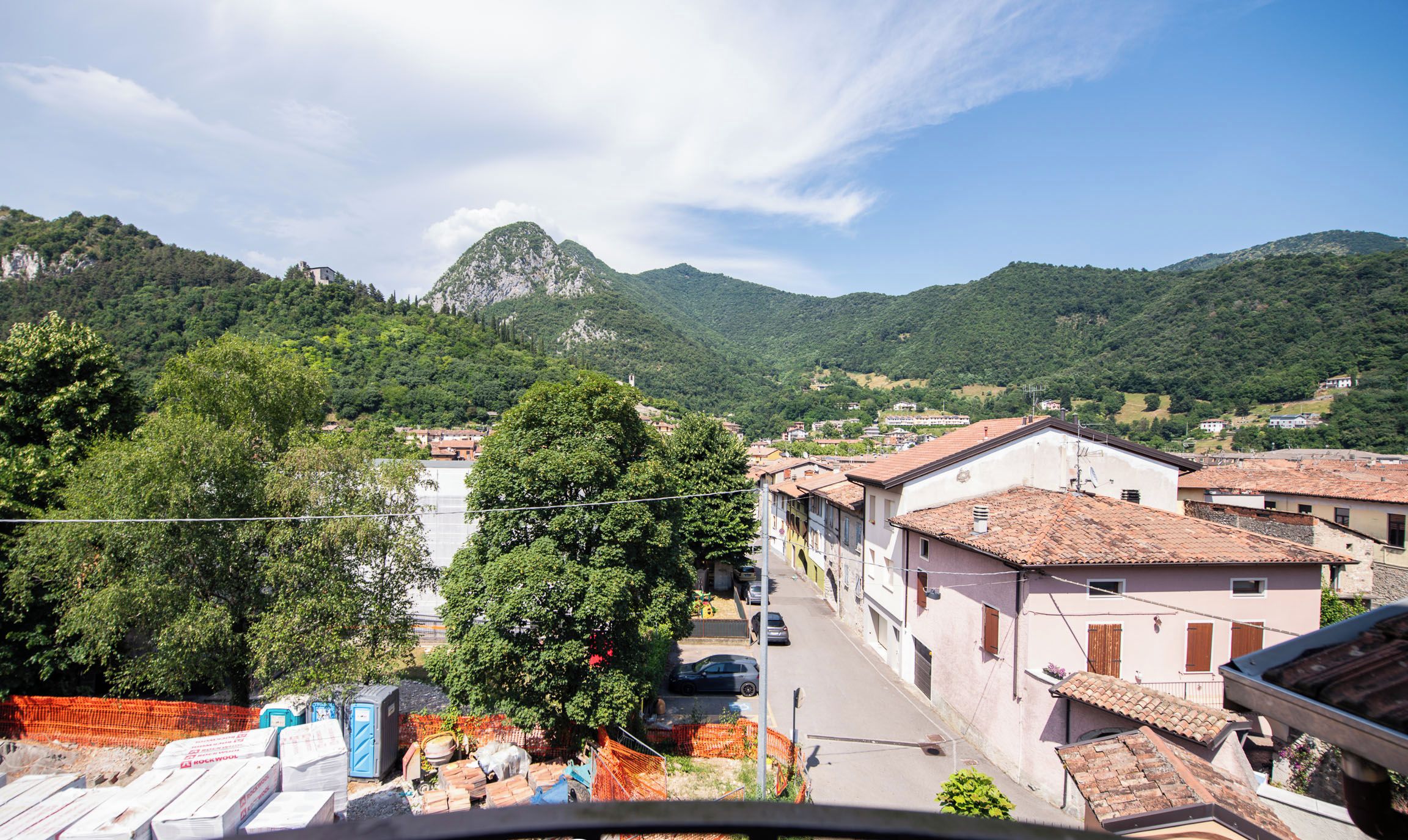 A view of a town with buildings, a mountain, and trees.
