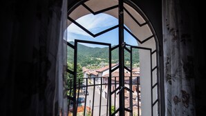 A view through a window with a geometric frame, revealing a street with buildings and a hilly landscape in the background.