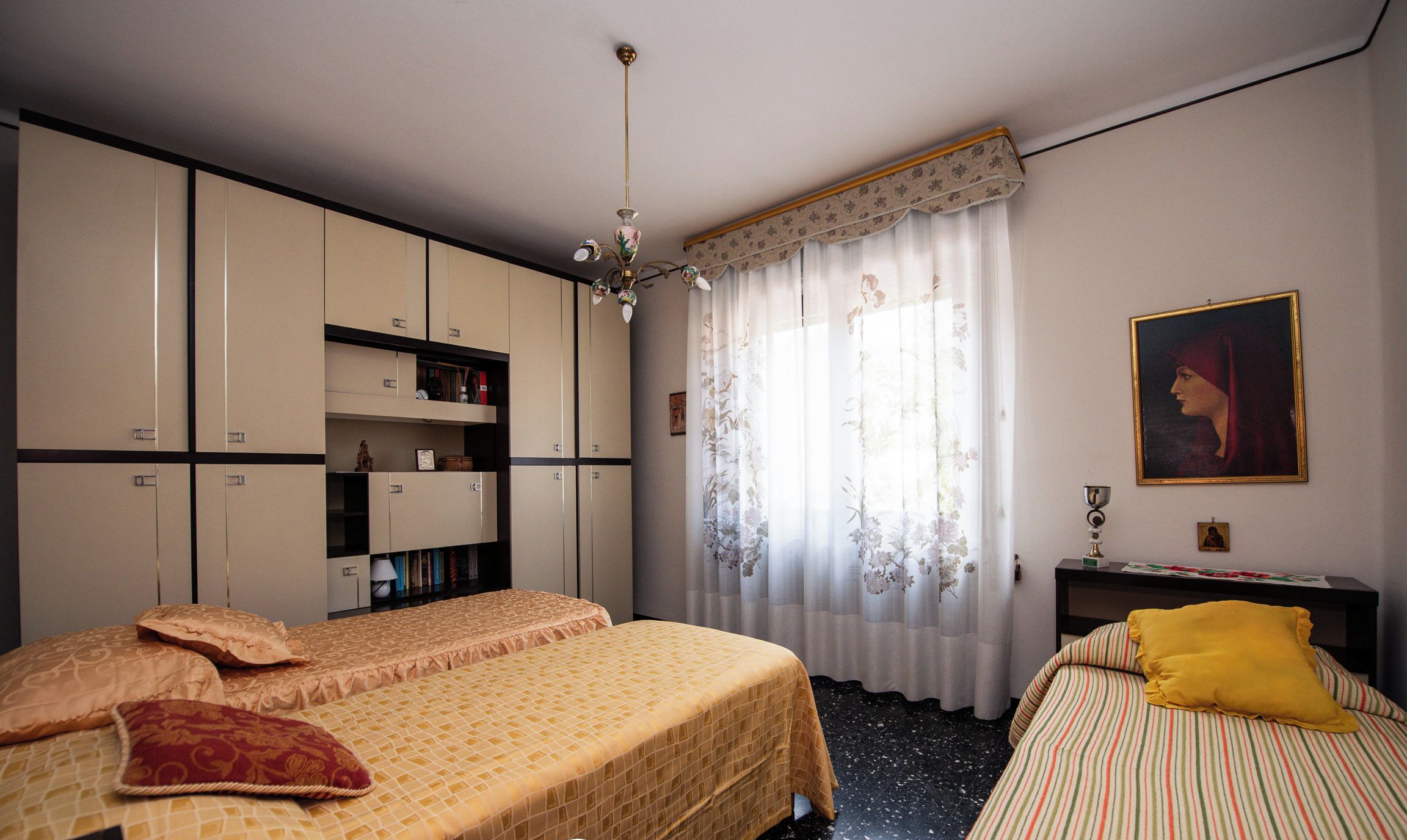 Une chambre d’hôtel avec deux lits, une armoire, un bureau et une fenêtre avec des rideaux.
