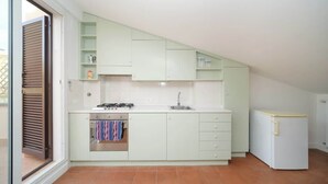 Een kleine keuken met een gasfornuis, oven en een koelkast.