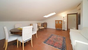 Een eethoek met een tafel en stoelen, een bank, een kast en een vloerlamp.