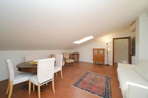 Ein Essbereich mit Tisch und Stühlen, einer Couch, einem Schrank und einer Stehlampe.