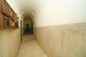 A narrow hallway with wooden cabinets on one side and a marble wall on the other. - BuddyRent - Juan's Trevi - Terrace - 6 guests (Roma)