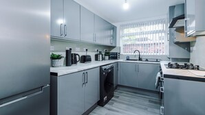 Una cocina moderna con electrodomésticos de acero inoxidable, lavadora integrada y un ventanal que proporciona luz natural.