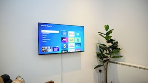 Ein flachbildfernseher an der Wand, der eine Streaming-Dienstoberfläche mit verschiedenen Optionen zeigt.