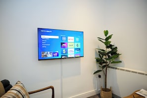Ein flachbildfernseher an der Wand, der eine Streaming-Dienstoberfläche mit verschiedenen Optionen zeigt.