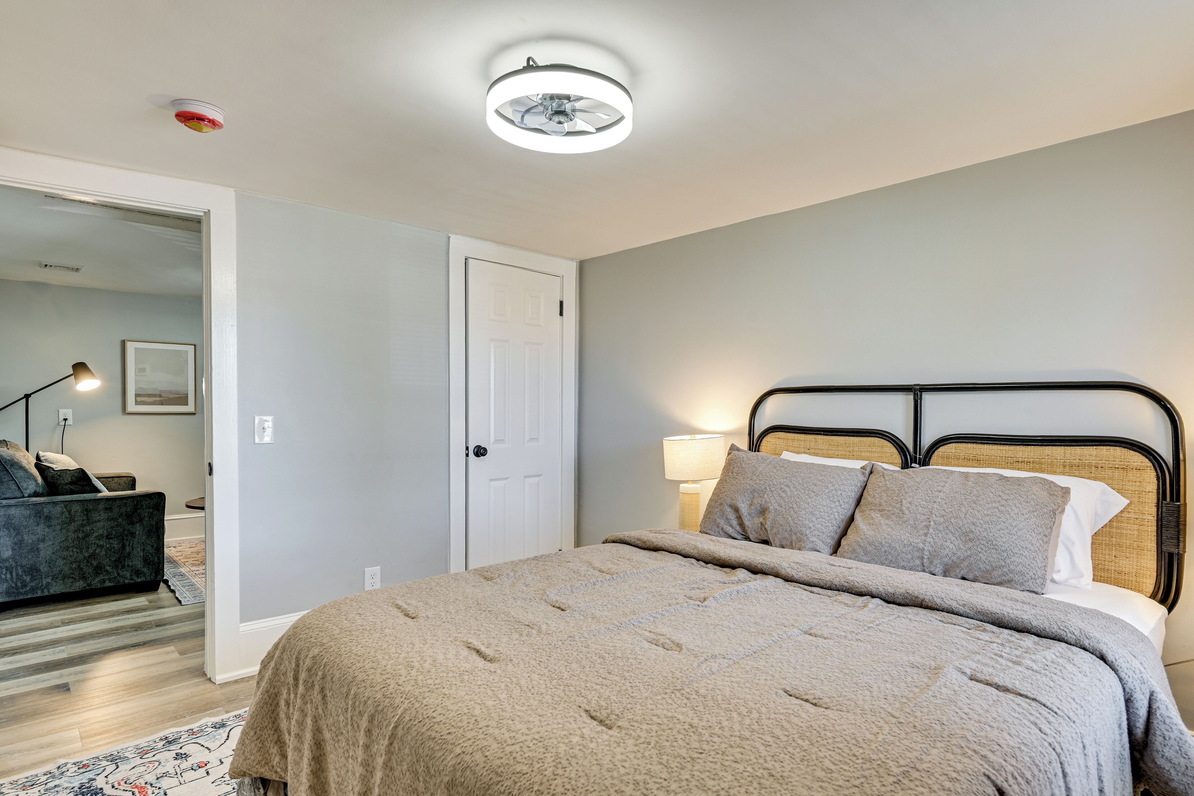 A bedroom with a bed, bedside lamp, and a door.