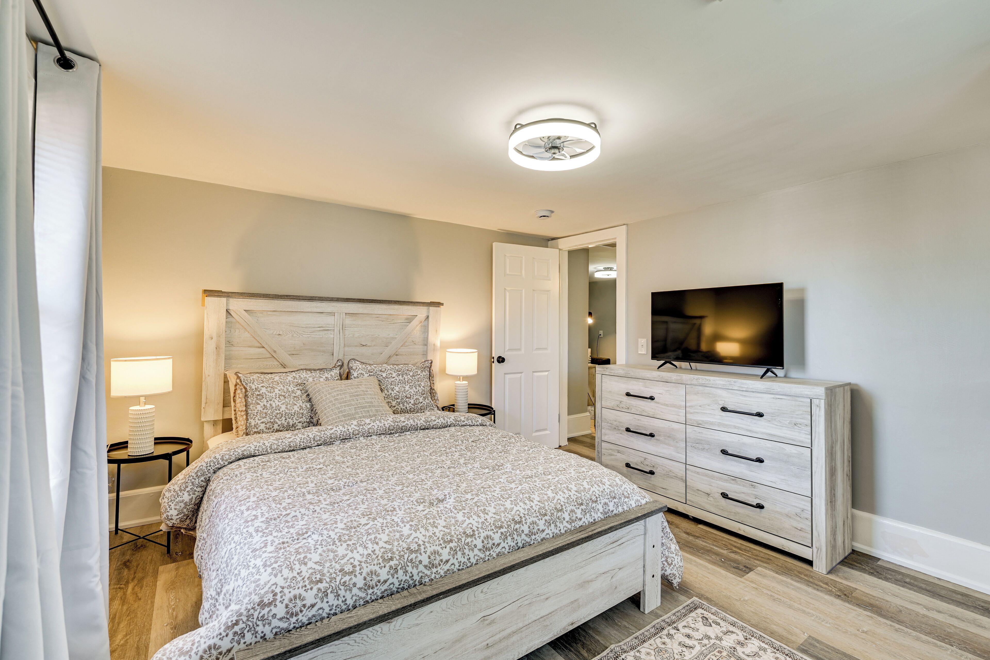 Un dormitorio con cama, mesitas de noche, cómoda, televisor y ventilador de techo.