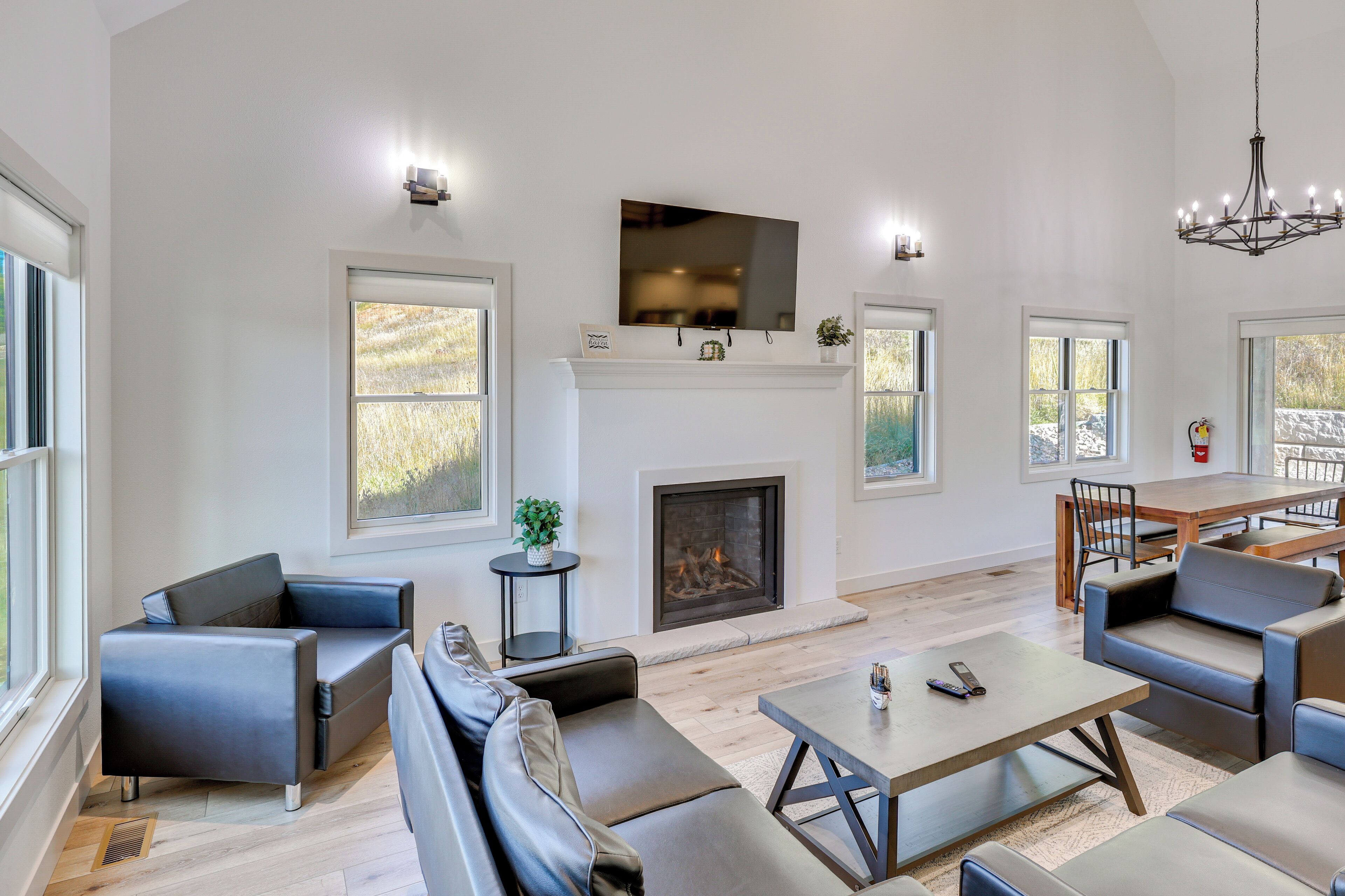 A spacious living room with a fireplace, modern furniture, and large windows.