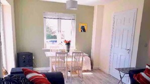 Un salon avec un canapé, une table à manger et des chaises, et une porte.