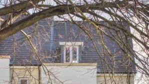 Un immeuble résidentiel de deux étages, doté d’une façade blanche, de quelques éléments décoratifs en pierre et d’un petit balcon.