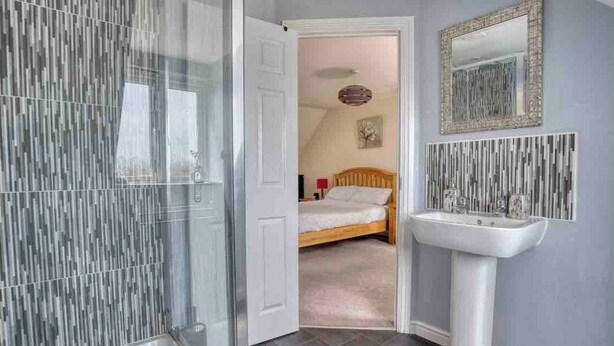 Une salle de bain avec une douche, un lavabo et un miroir.