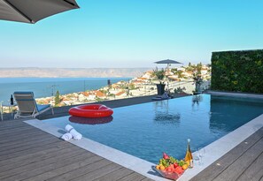 Una piscina al aire libre, sombrillas, sillones reclinables de piscina