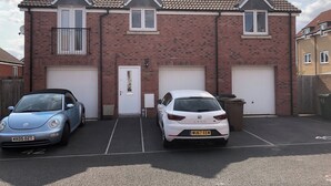 A two-story brick house with a tiled roof and two garage doors. - Entire Two Bedroom Detached Coach House (Exeter)