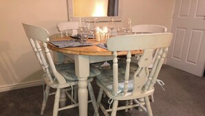 A dining table with four chairs, a candle, and several wine glasses. - Entire Two Bedroom Detached Coach House (Exeter)
