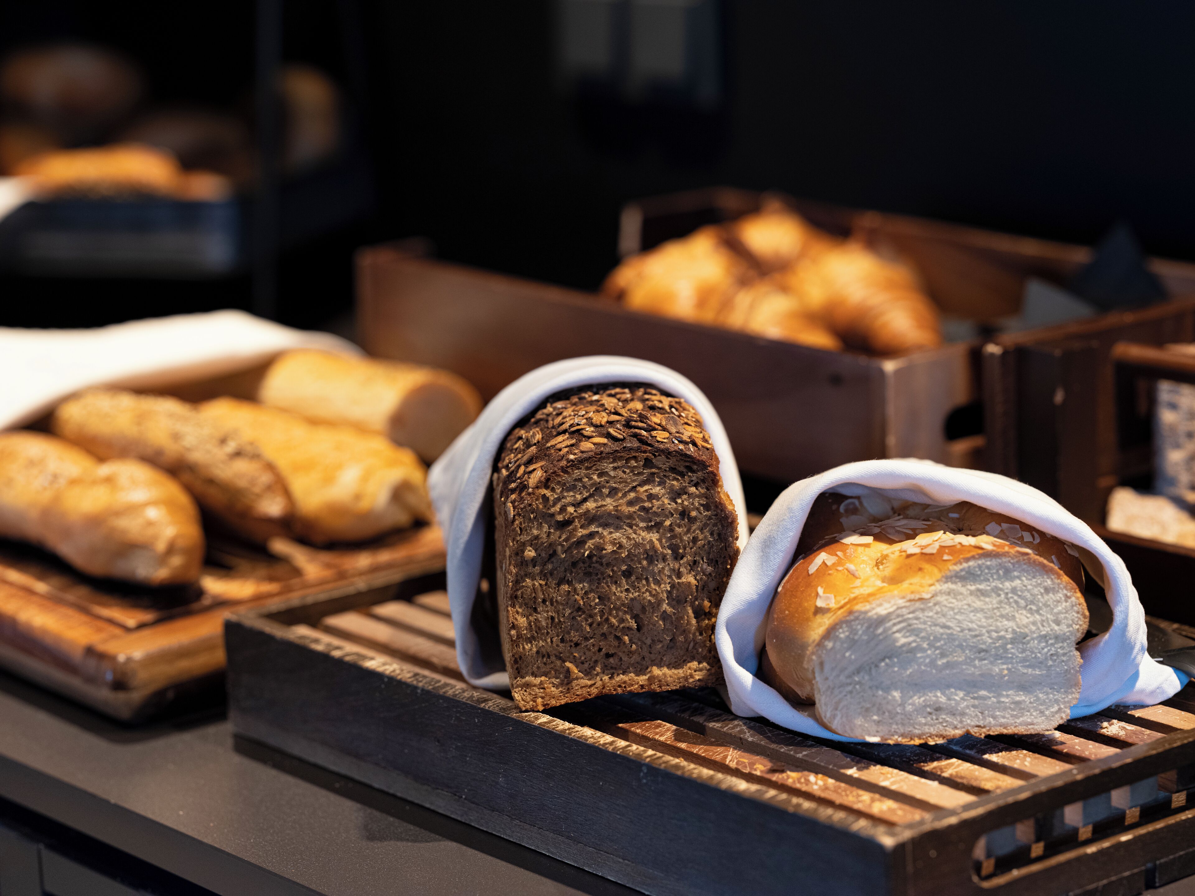 A variety of breads displayed on wooden boards in a bakery setting.