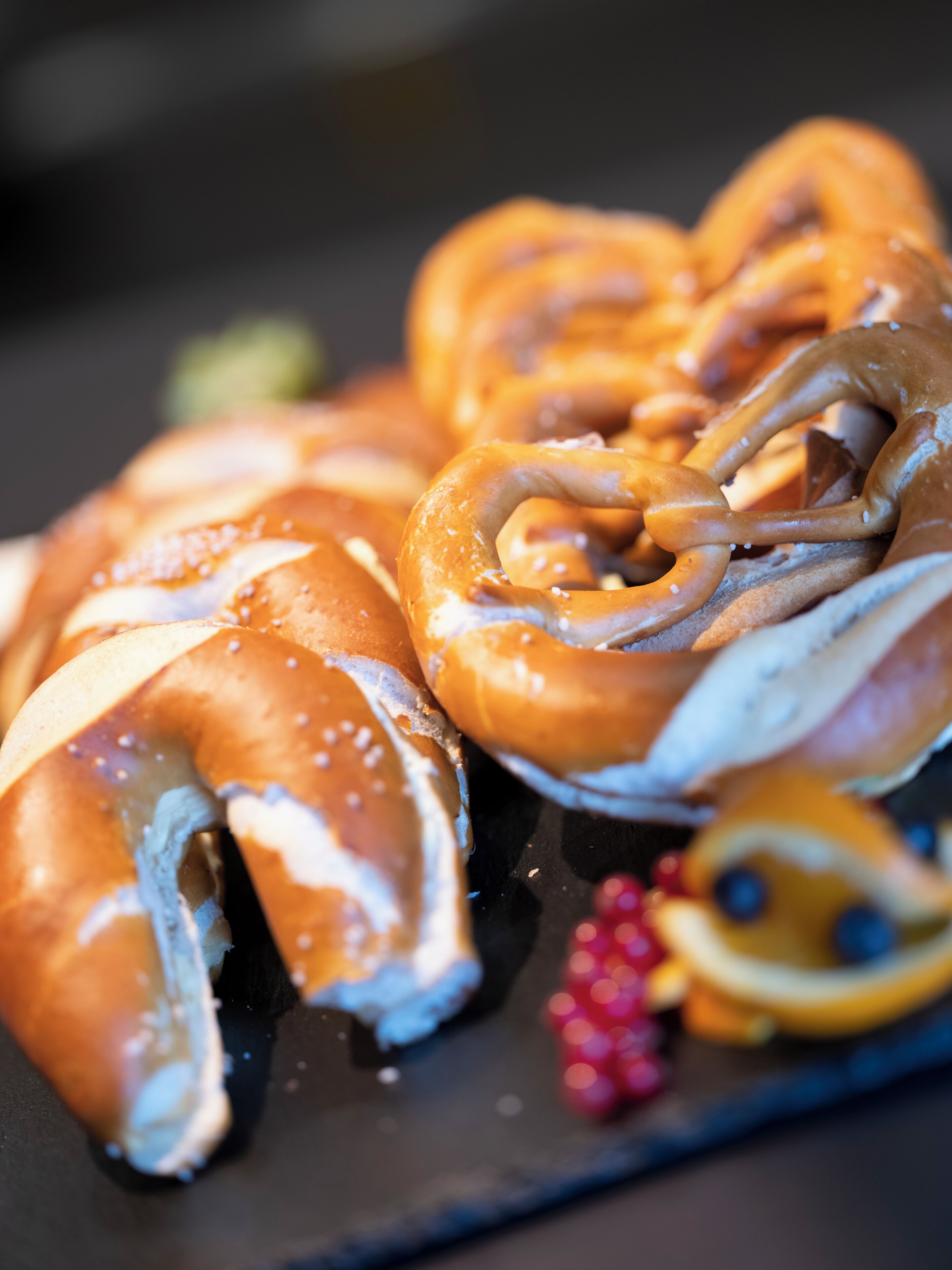 Primer plano de pretzels con un acabado brillante, posiblemente glaseados o cubiertos, y espolvoreados con sal.