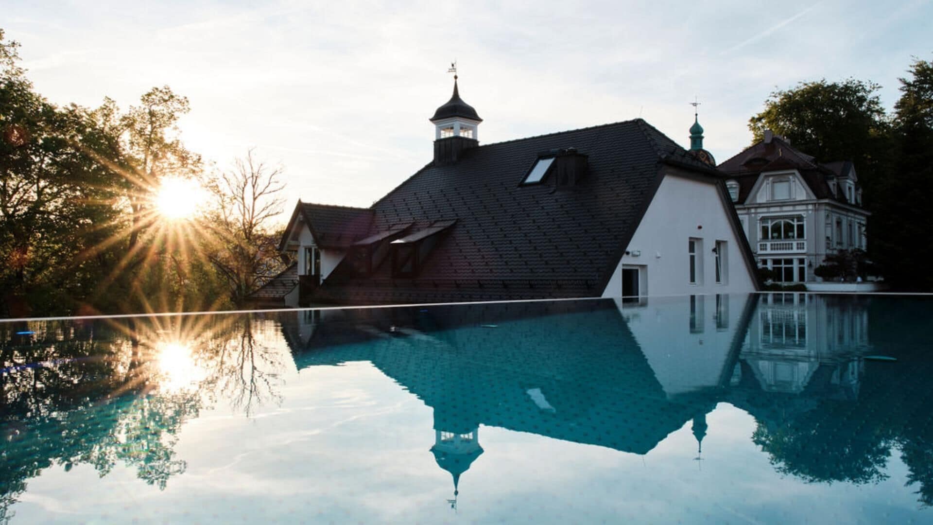 Ein großes Haus mit Swimmingpool, einem Turm und einem Sonnenreflex.
