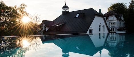 Ein großes Haus mit Swimmingpool, einem Turm und einem Sonnenreflex.